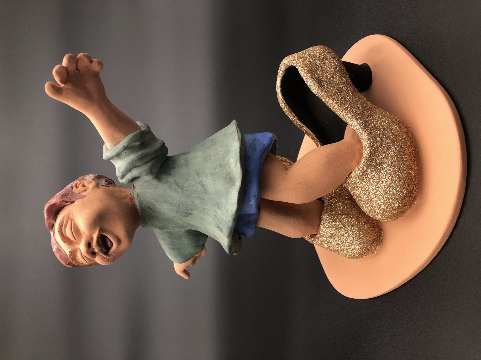 Figure en céramique d'enfant qui a mis des grandes chaussures à talons