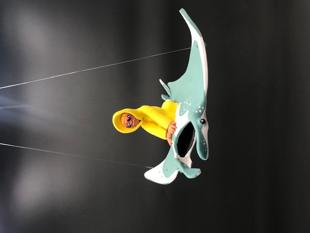 Mobile en argile du personnage en ciré jaune et lunnettes de coeur rouges sur une manta