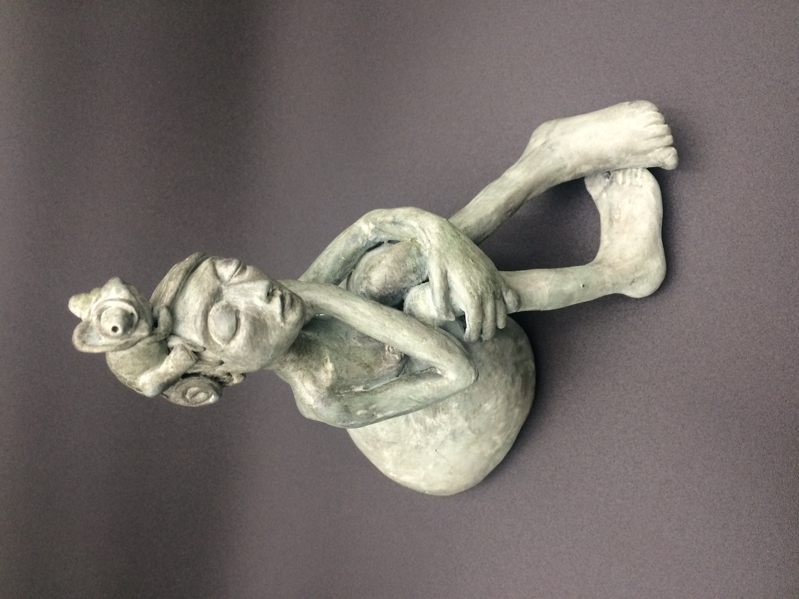 Pièce céramique femme nue assise, les jambes pliés. Elle a un caméléon sur la tête.