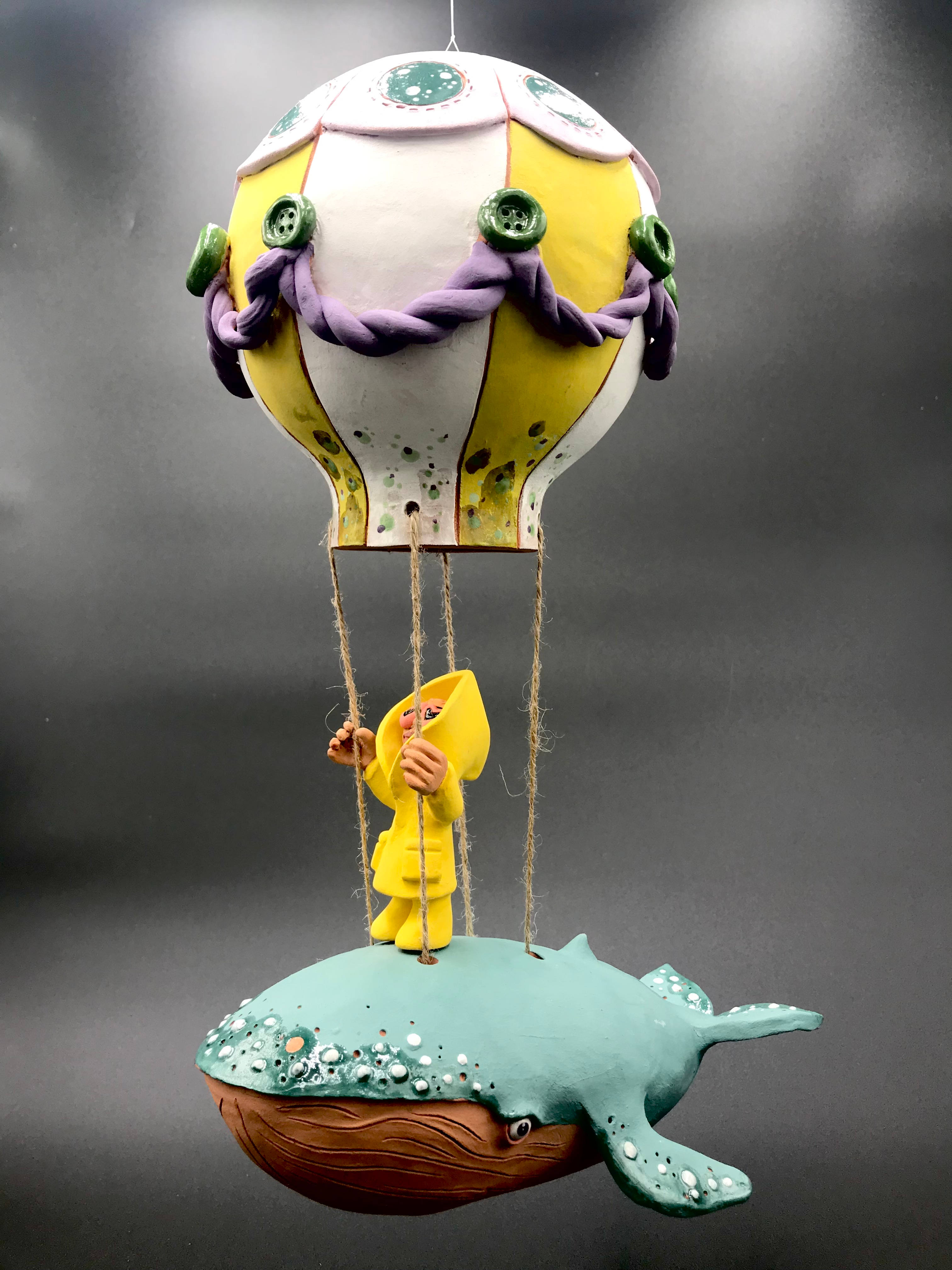 Pièce en céramique du personnage en ciré jaune montée sur un montgolfière dont la base est un baleine.