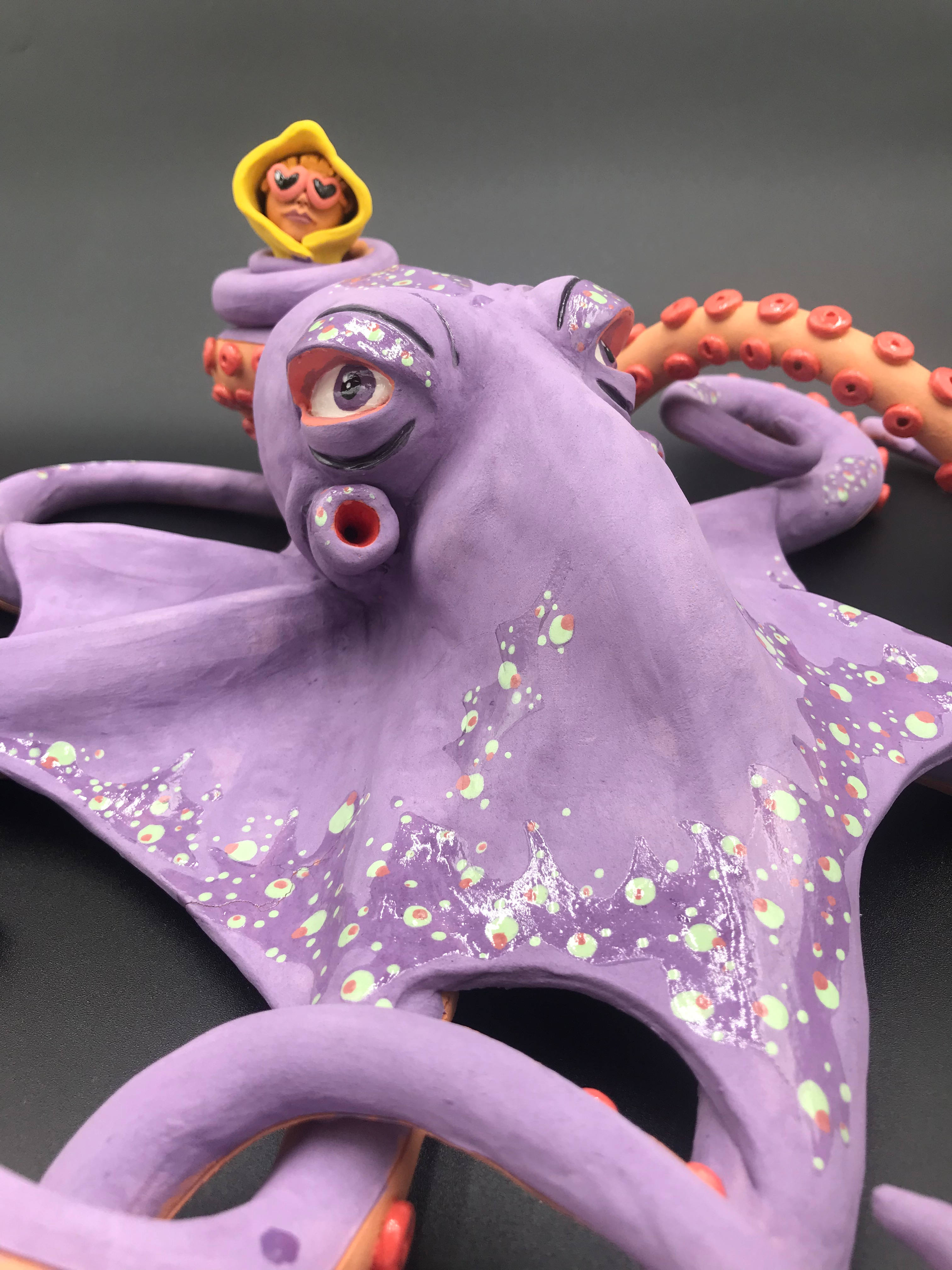 Sculture céramique Poulpe mauve qui tient dans un de ses teentacules le personnage au ciré jaune et lunnettes de coeur.