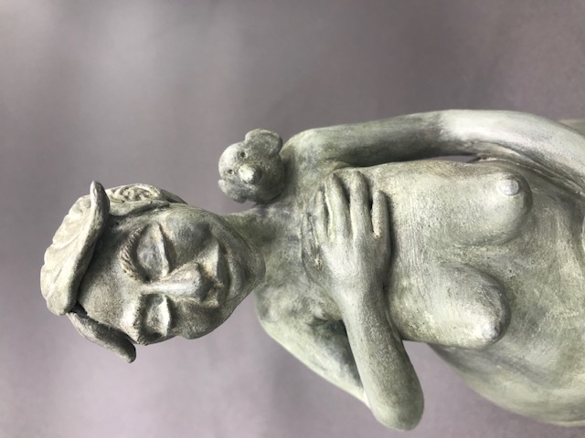 Céramique de femme seins nus avec la main sur le coeur et un oiseau sur l'épaule.