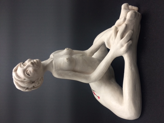 Sculpture en céramique d'une femme aux cheveux courts nue et assise avec les jambes en triangle. Les mains reposent sur les pieds.