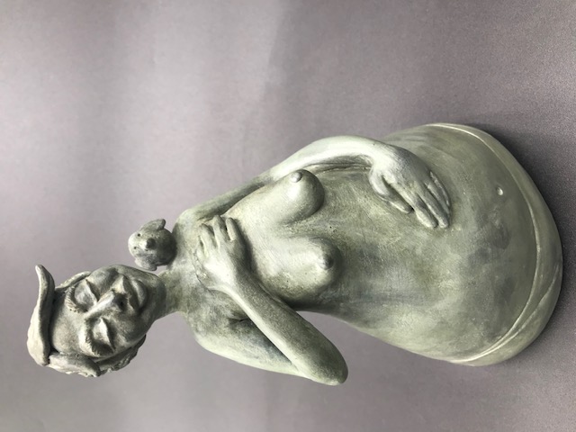 Céramique de femme seins nus avec la main sur le coeur et un oiseau sur l'épaule. Elle a une main sur son ventre et l'autre sur sa poitrine.