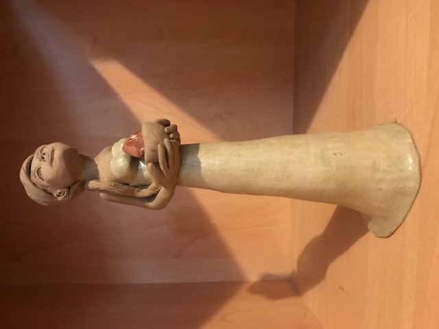 Petite sculpture en céramique d'une femme mince à la robe longue. Elle a une longue queue et regarde vers le haut. El porte dans ses mains un bol avec un minéral.