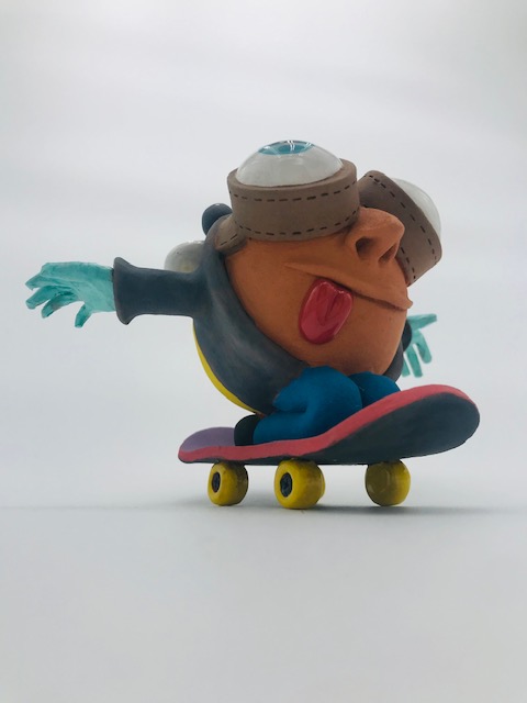 Céramique d'enfant à tête géante à genoux sur skate. Il a des grands yeux et ouvre ses bras.