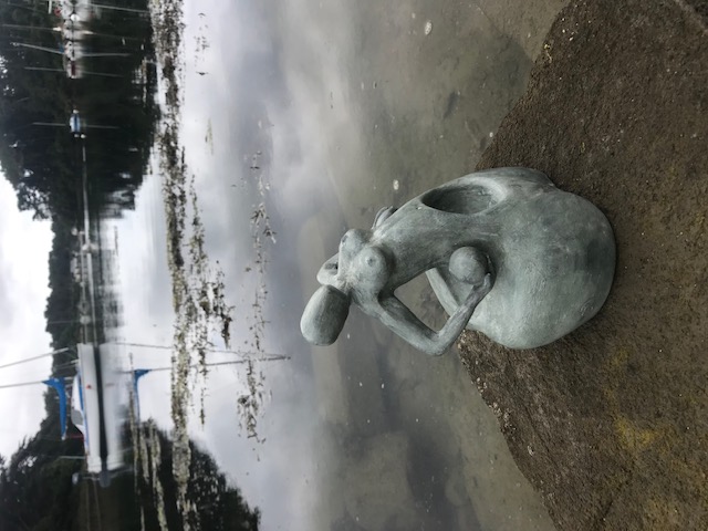 Sculpture en céramique d'une forme féminine sans visage au ventre creux qui soutient une sphère contre son hanche.