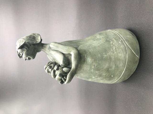 Céramique de femme seins nus soutenant un bébé qui dort.