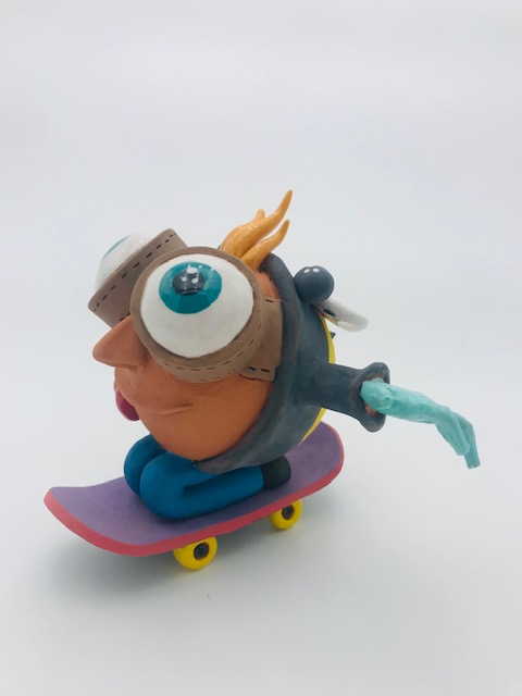 Céramique d'enfant à tête géante à genoux sur skate. Il a des grands yeux et ouvre ses bras.