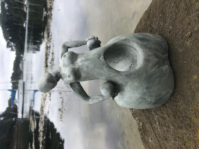 Sculpture en céramique d'une forme féminine sans visage au ventre creux qui soutient des sphères contre ses hanches.