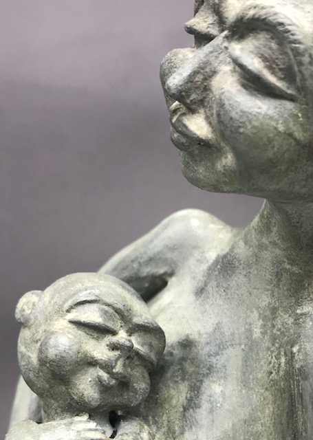 Céramique de femme seins nus soutenant un bébé qui dort.