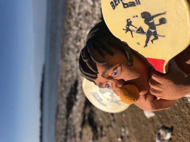 Petite fille avec une balle en mousse dans la bouche et avec raquette dans les mains