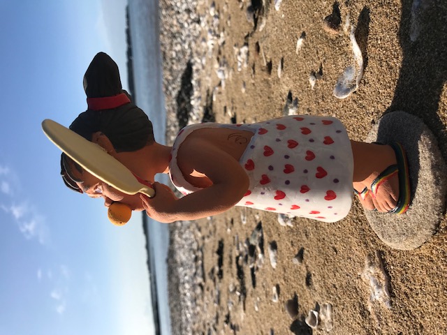 Petite fille avec une balle en mousse dans la bouche et avec raquette dans les mains