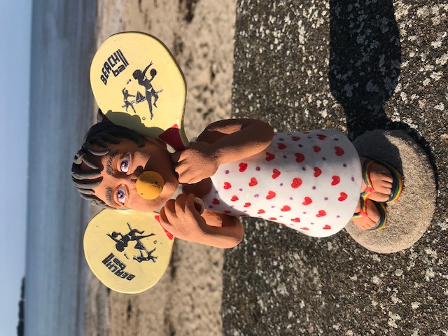 Petite fille avec une balle en mousse dans la bouche et avec raquette dans les mains