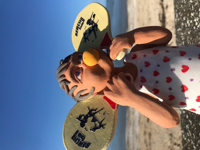 Petite fille avec une balle en mousse dans la bouche et avec raquette dans les mains