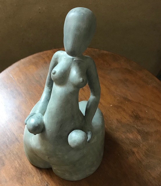 Femme en argile qui soutient deux grands œufs