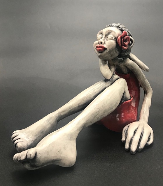 Jeune fille en céramique émaillée avec une robe rouge, de grandes mains et grands pieds avec une rose rouge à l'oreille