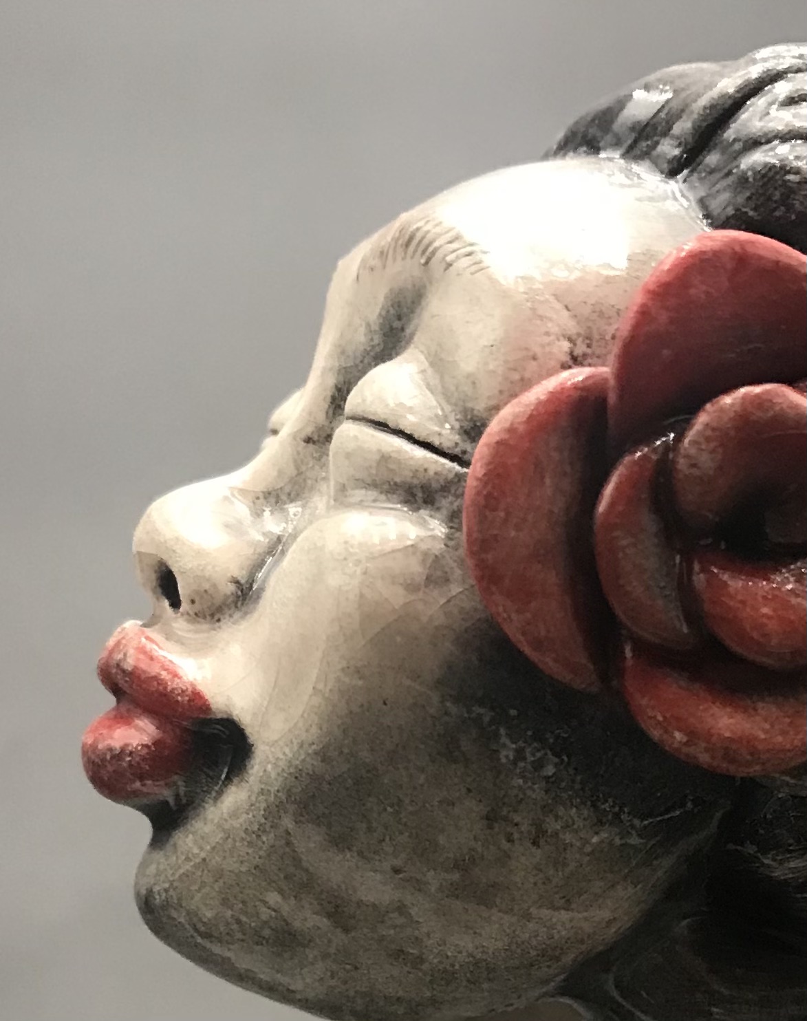 Jeune fille en céramique émaillée avec une robe rouge, de grandes mains et grands pieds avec une rose rouge à l'oreille