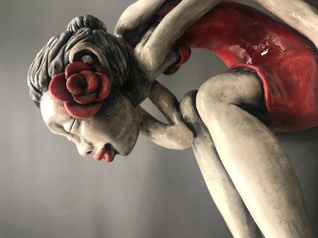 Jeune fille en céramique émaillée avec une robe rouge, de grandes mains et grands pieds avec une rose rouge à l'oreille