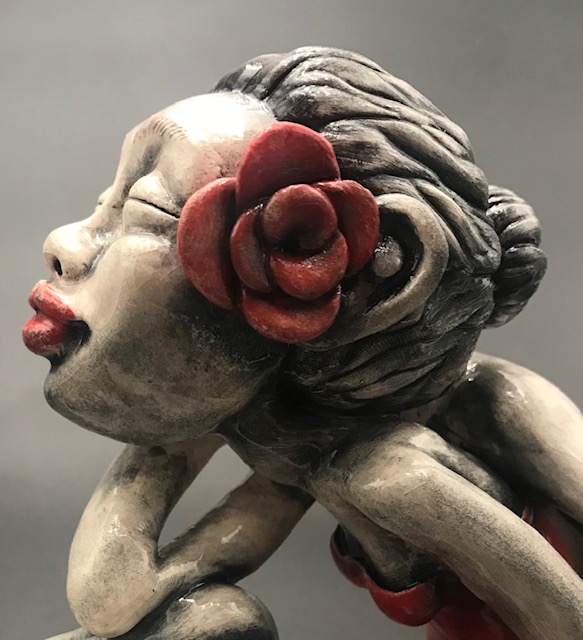 Jeune fille en céramique émaillée avec une robe rouge, de grandes mains et grands pieds avec une rose rouge à l'oreille