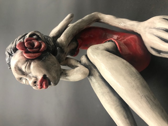 Jeune fille en céramique émaillée avec une robe rouge, de grandes mains et grands pieds avec une rose rouge à l'oreille