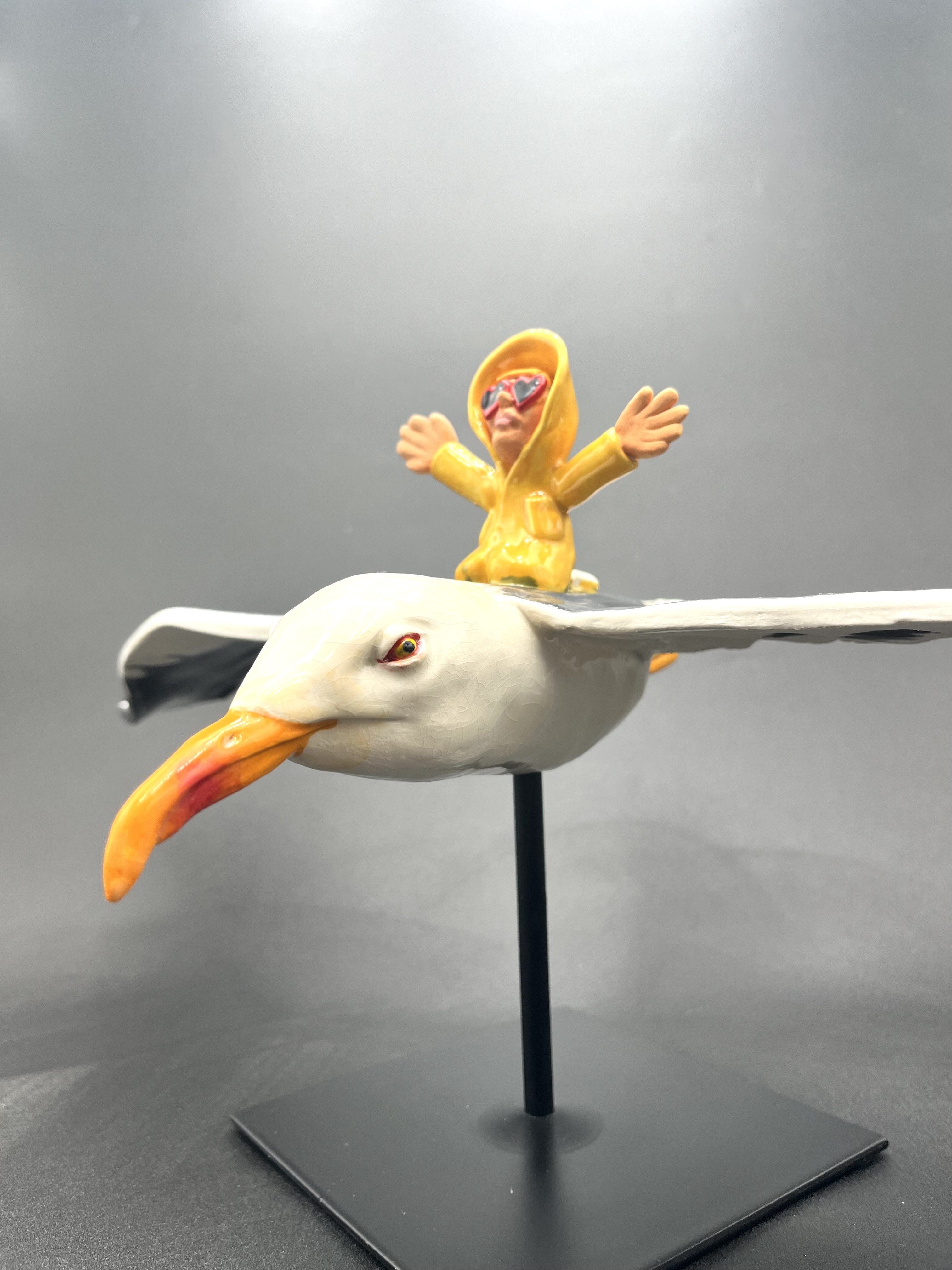 Sculpture céramique d'un petit personnage en ciré chevauchant un goéland