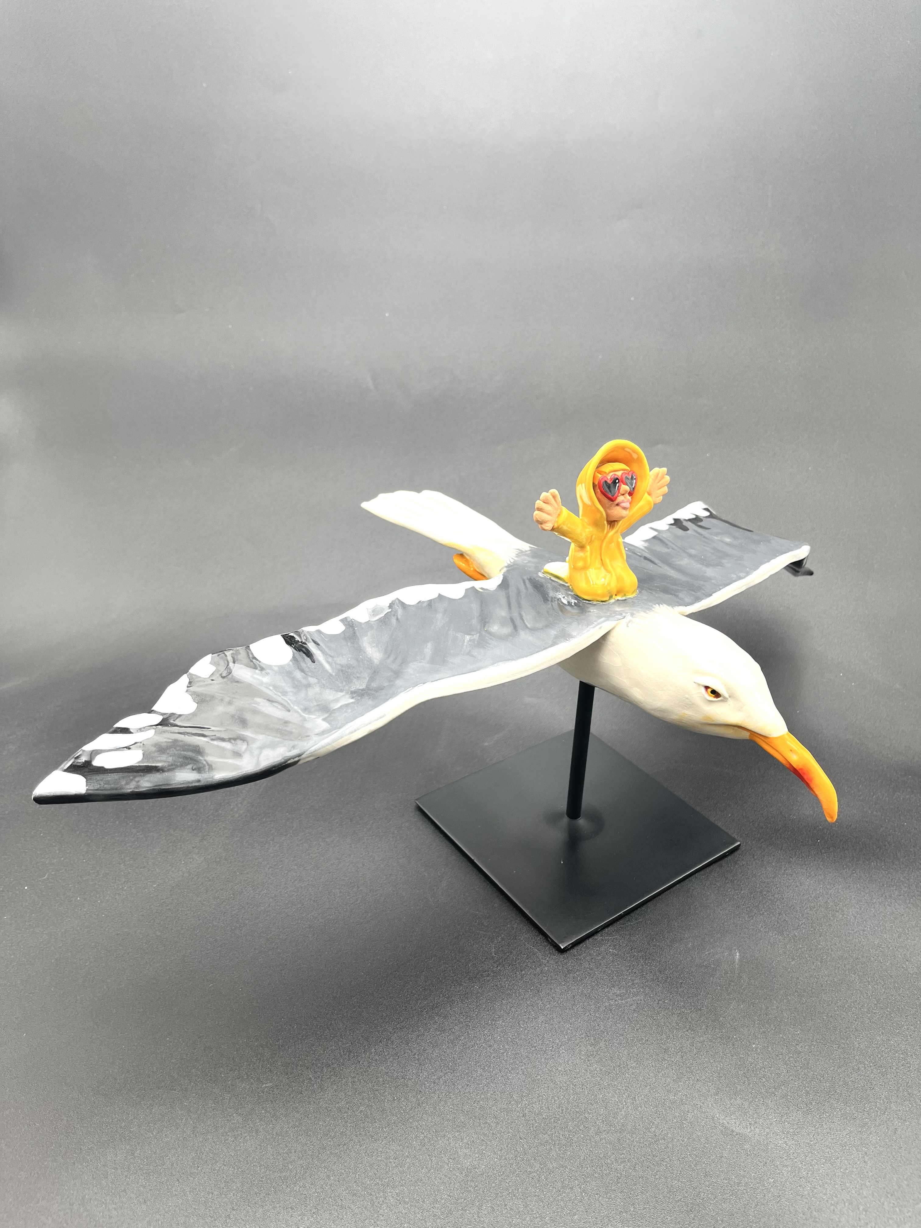 Sculpture céramique d'un petit personnage en ciré chevauchant un goéland