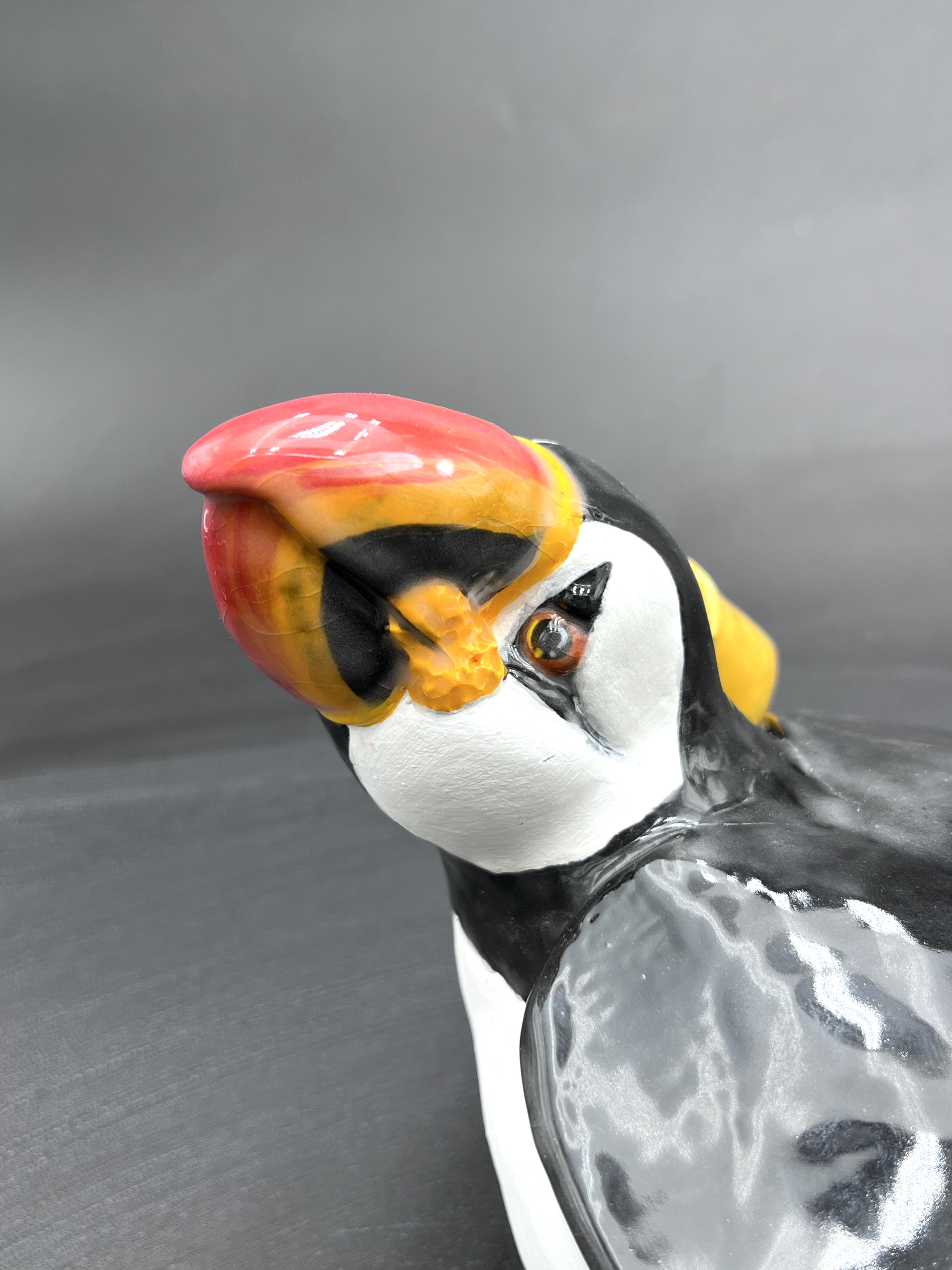 Sculpture en céramique d'un petit personnage en ciré faisant un calin à un macareuxSculpture en céramique d'un petit personnage en ciré faisant un calin à un macareux