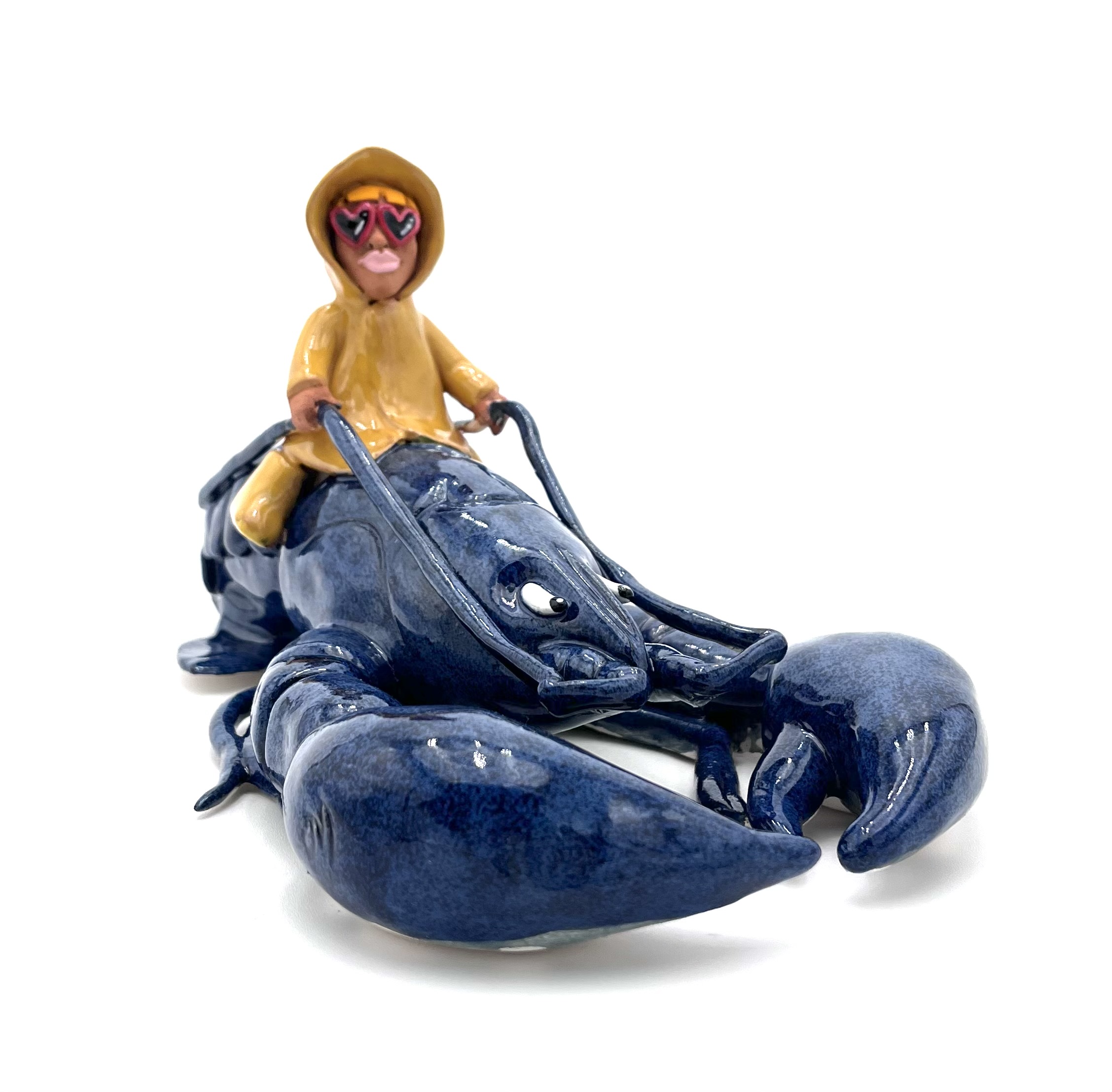 Sculpture en céramique d'un petit personnage en ciré jaune chevauchant un homard bleu
